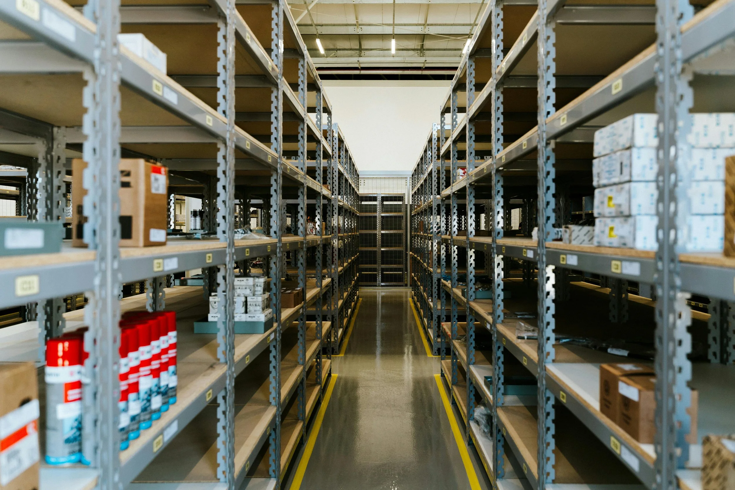 Empty industrial warehouse shelves with a wide aisle between them.