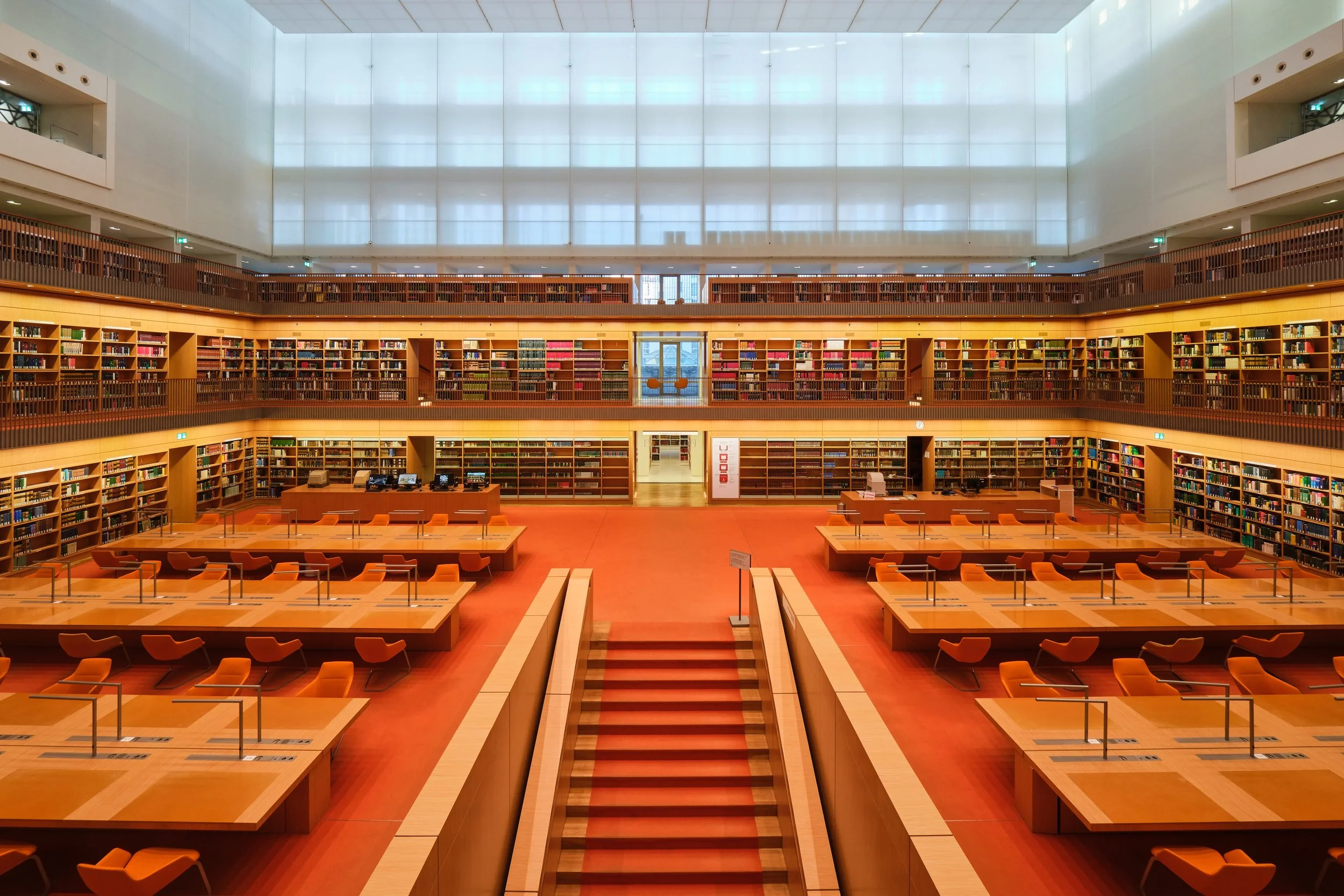 Mehrstöckige moderne Bibliothek mit viele Bücherregale, bequemem Lesebereich und großem Oberlicht.