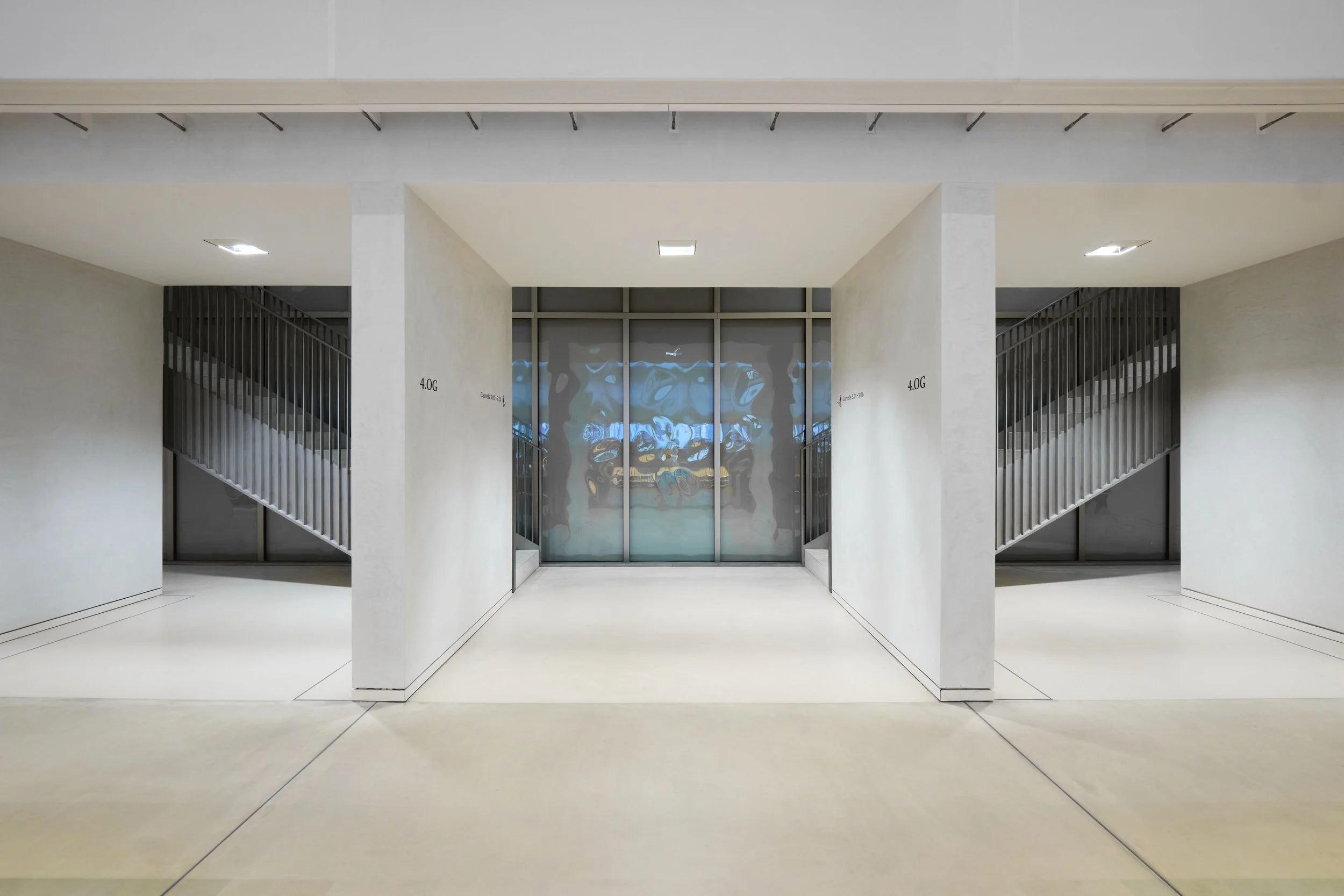 Modernes, minimalistisches Foyer mit weißen Wänden, Flur, Treppenaufgängen auf beiden Seiten und einer großen Tür in der Mitte.