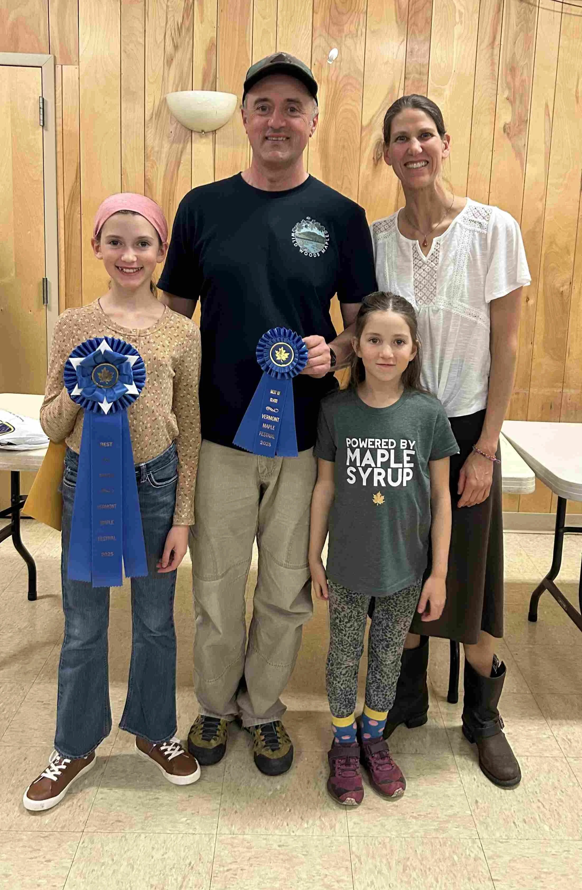 Our organic Vermont maple syrup won "Best in Show" at the 2025 Vermont Maple Festival. This is a picture of our family being presented our blue ribbons.