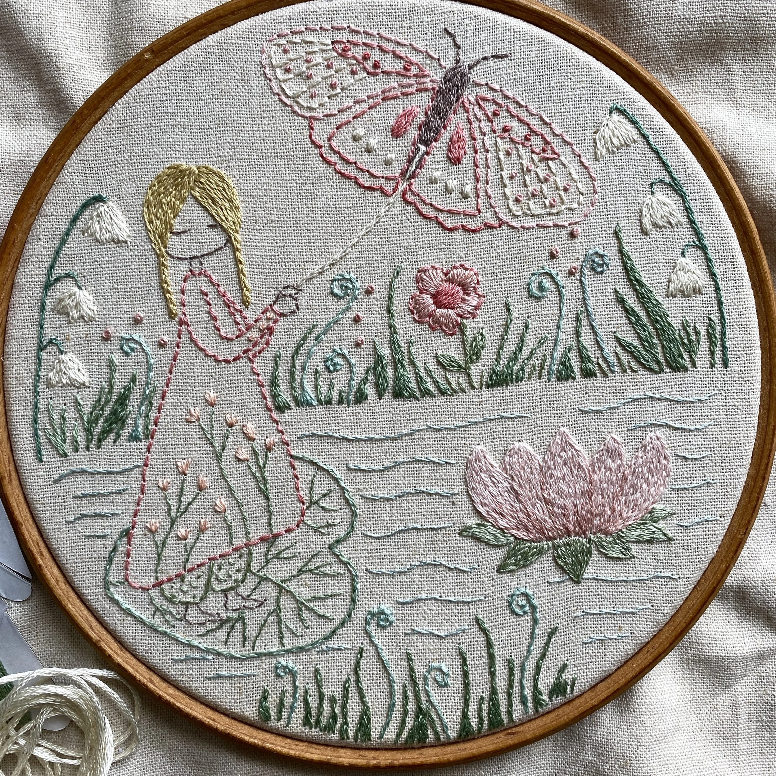 embroidery of a tiny girl floating on a leaf with a butterfly
