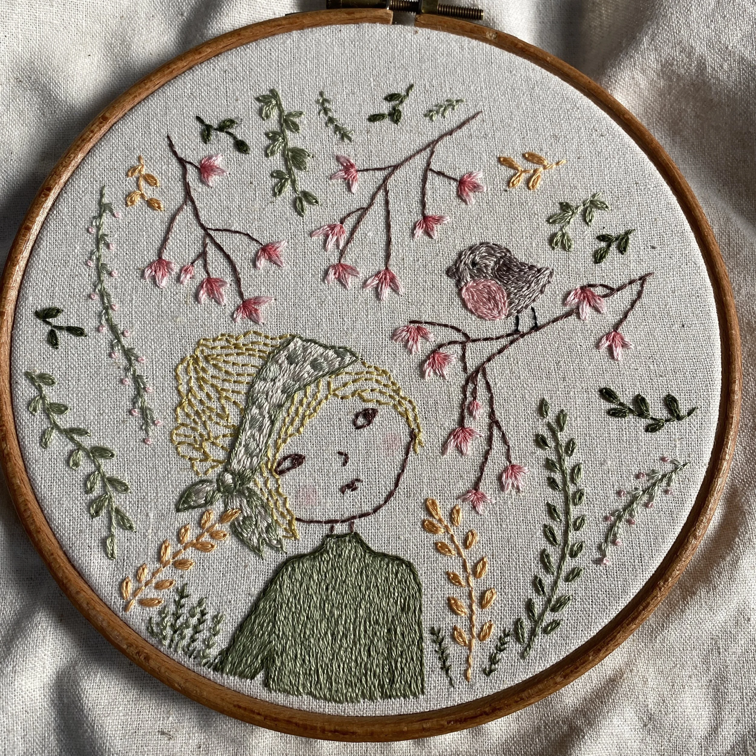 an embroidery of a girl looking at a bird on a branch