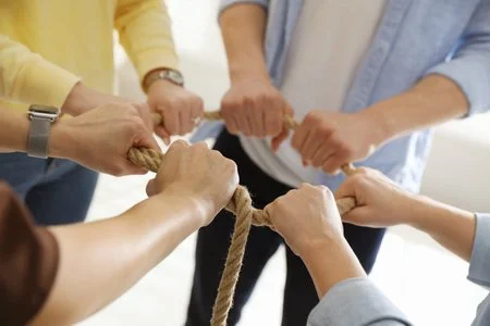 People in a team pulling on a rope during a team-building activity.