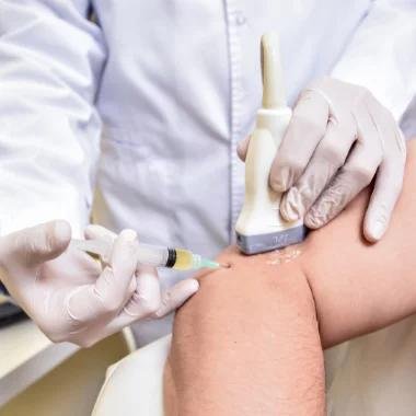 Médico realizando una inyección en el brazo de un paciente con guantes y equipo médico.