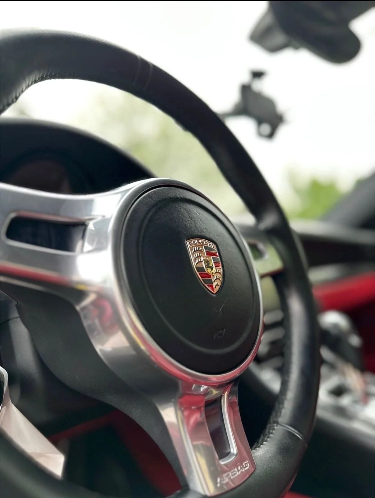 Close-up of a Porsche steering wheel inside a car.