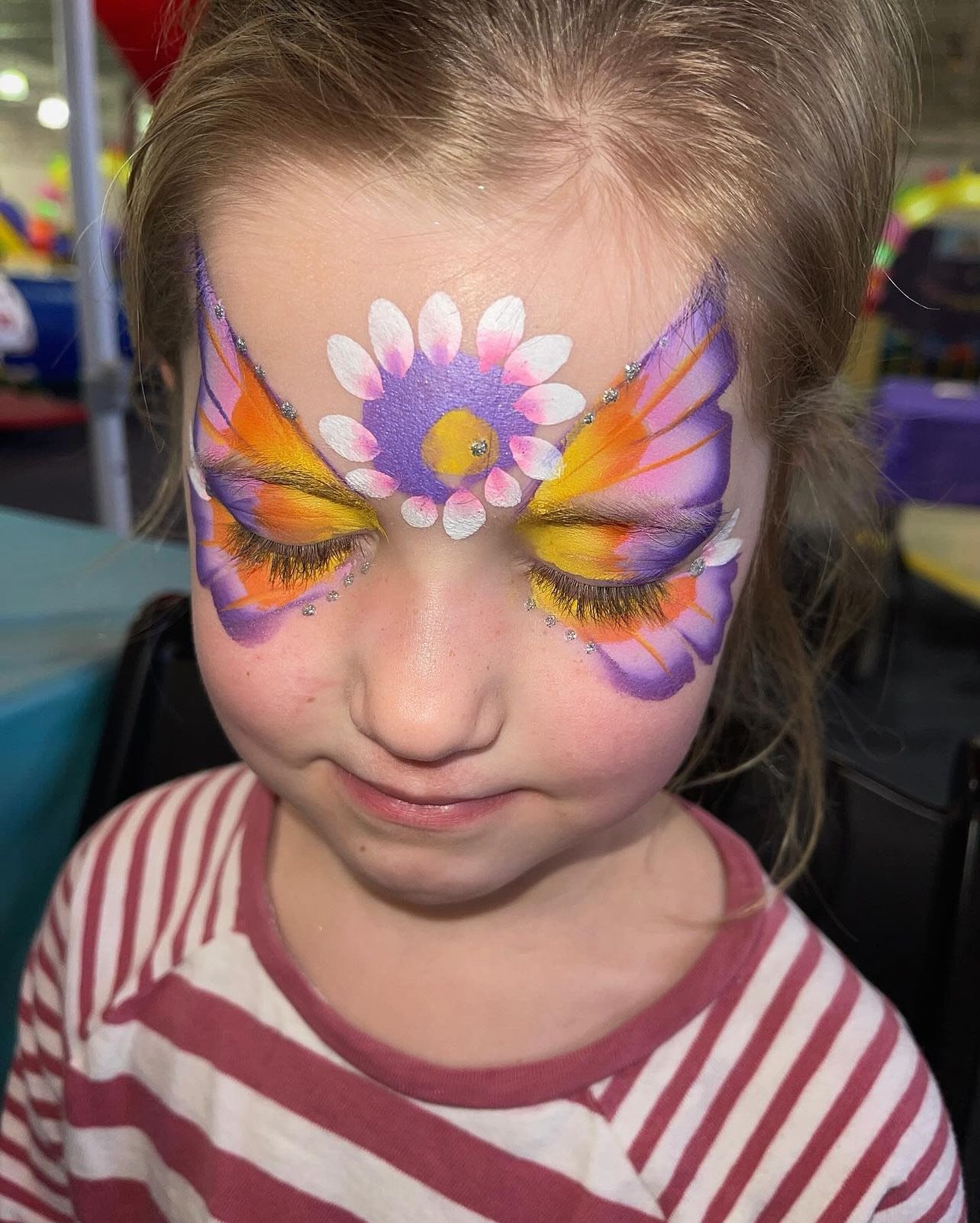  A child with their face painted in a butterfly pattern 