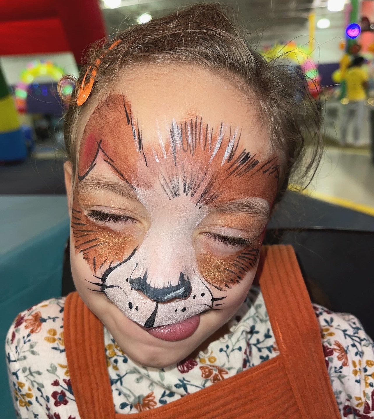  A child with their face painted in a woodland animal pattern 