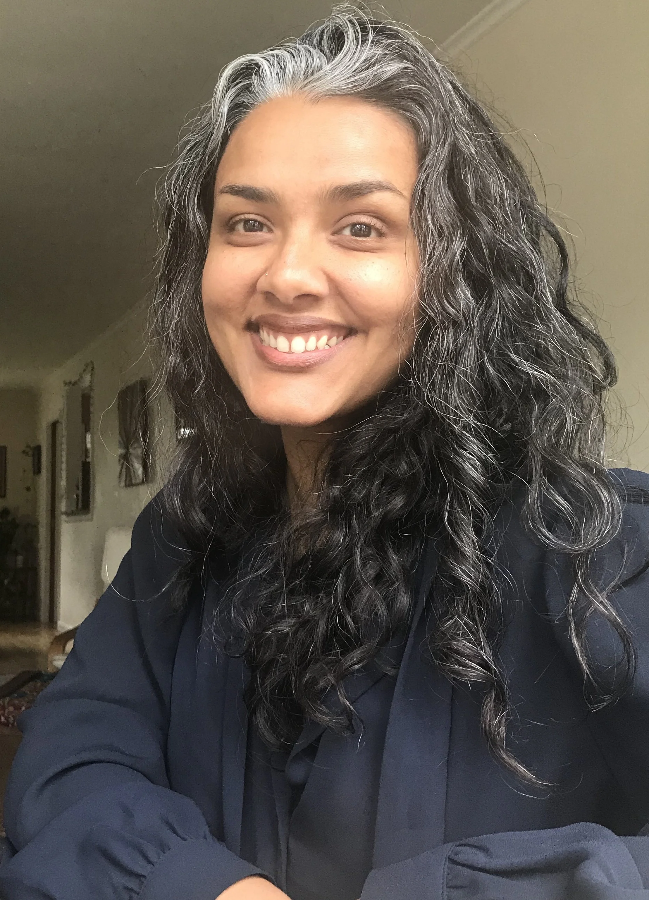 a photo of chancy, a brown-skinned person with salt and pepper curly hair. in the photo, chancy is smiling.