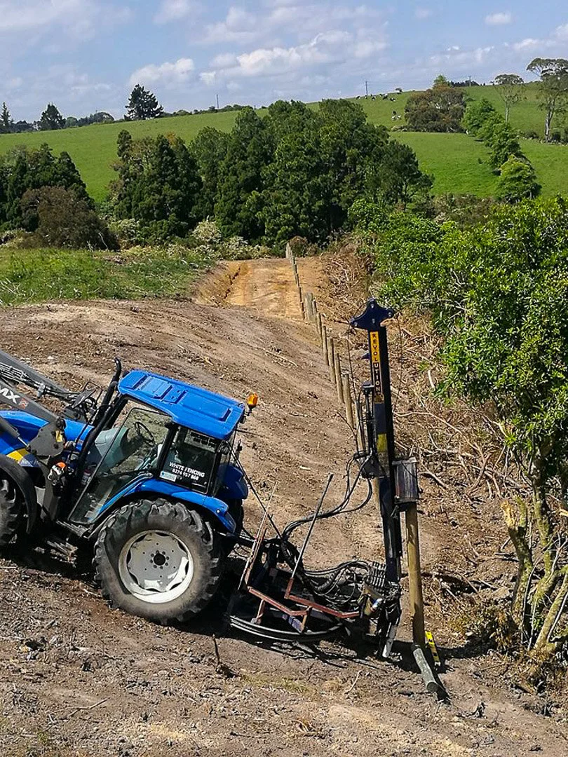 post driver and tractor ramming wood fence poles in field