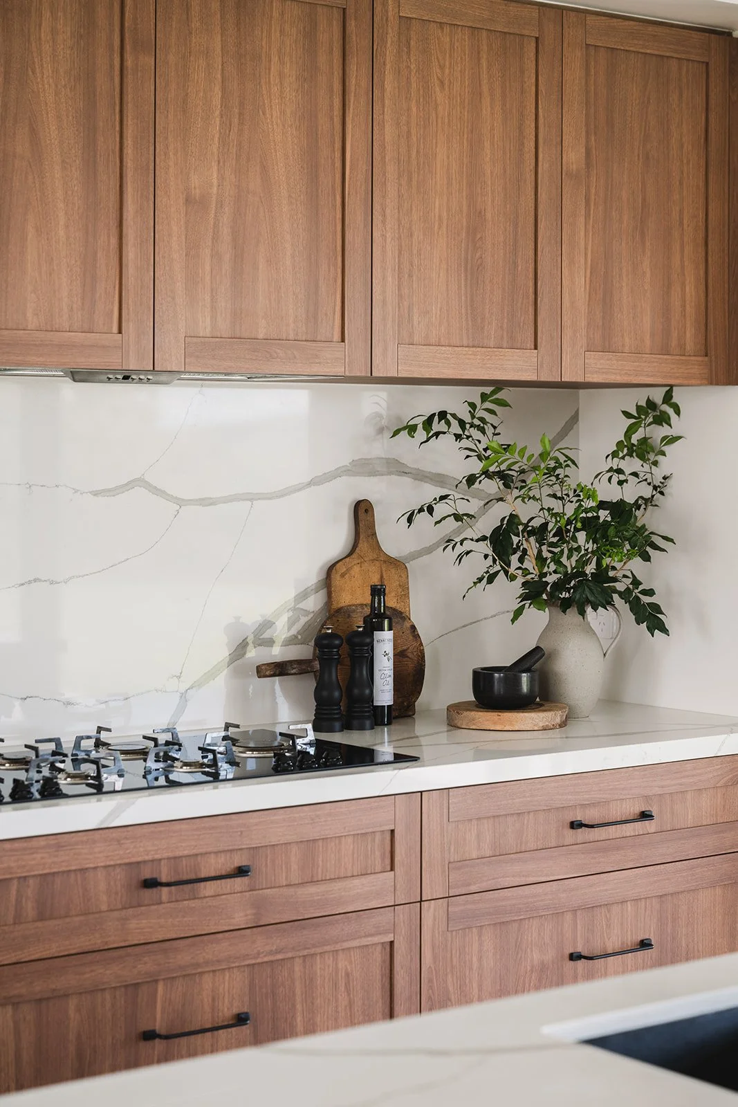 Kitchen with wooden cabinets, a white countertop, green plants, a kitchen mortar and pestle, and decorative items on the counter.