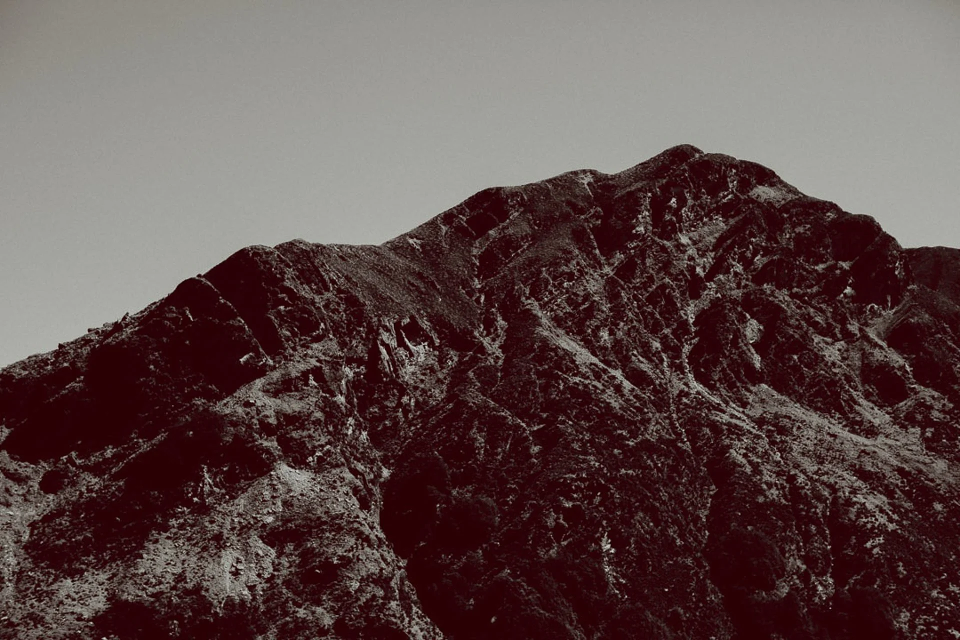 A black and white photo of a mountain range with rugged, steep peaks.