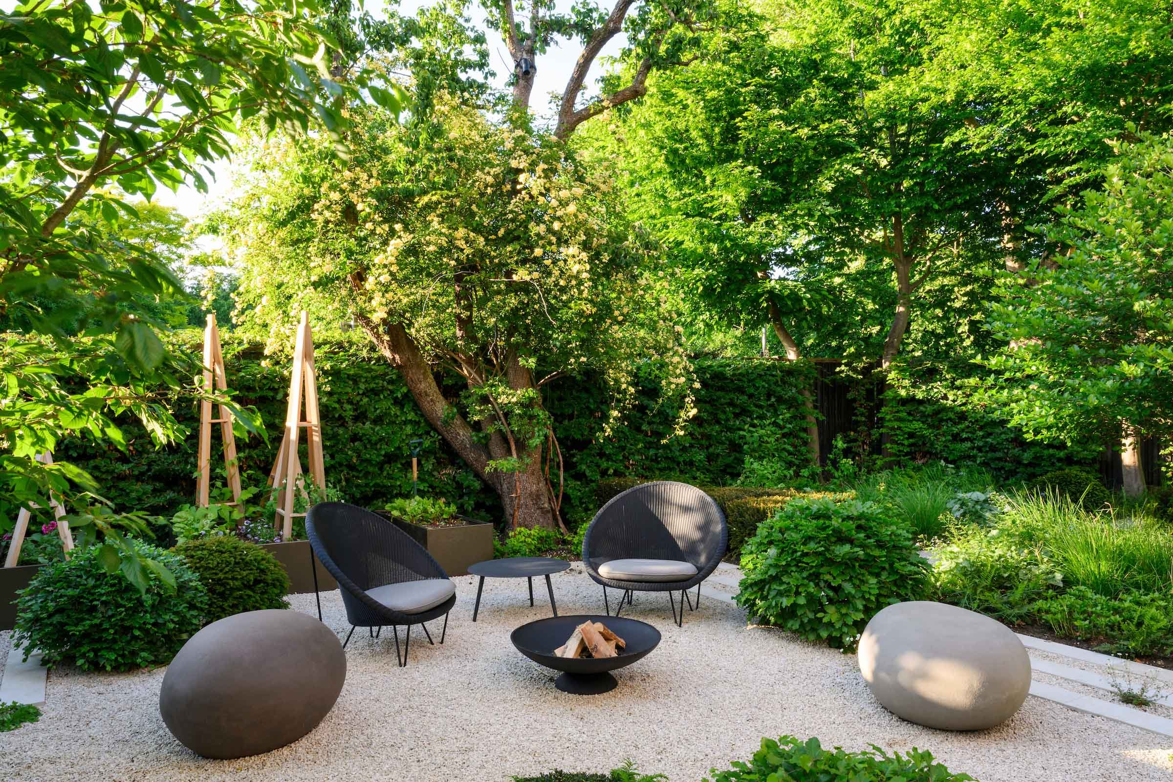 ravel seating terrace with chairs, fire pit and stone seats among shade-tolerant planting in a Putney side garden by Kawauchi Rowe