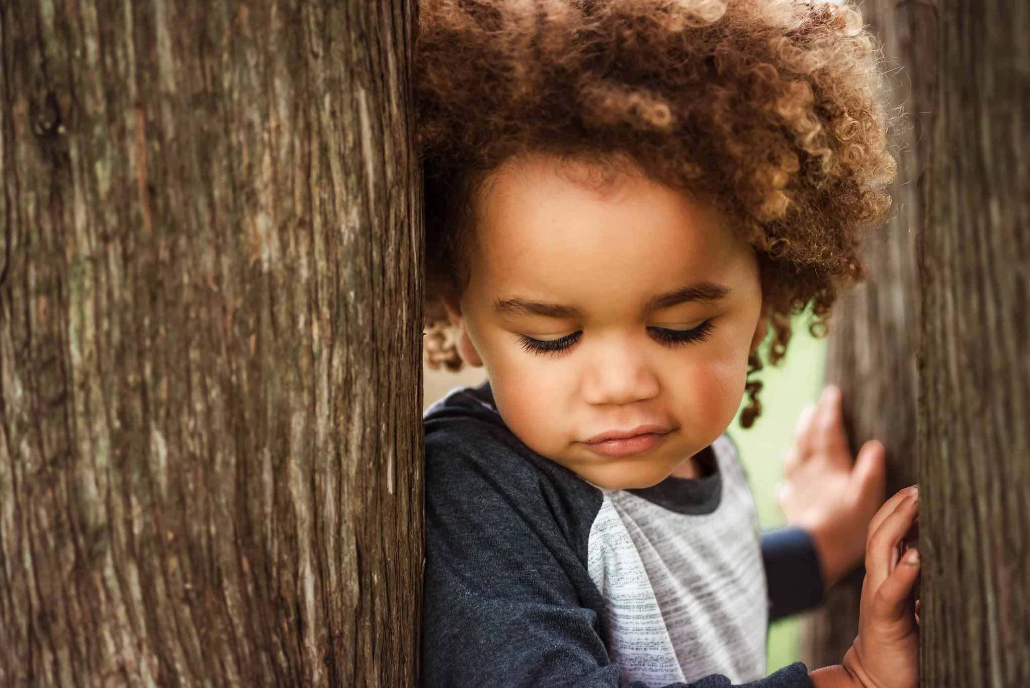 child hiding playfully during outdoor family photo session in charlotte, nc