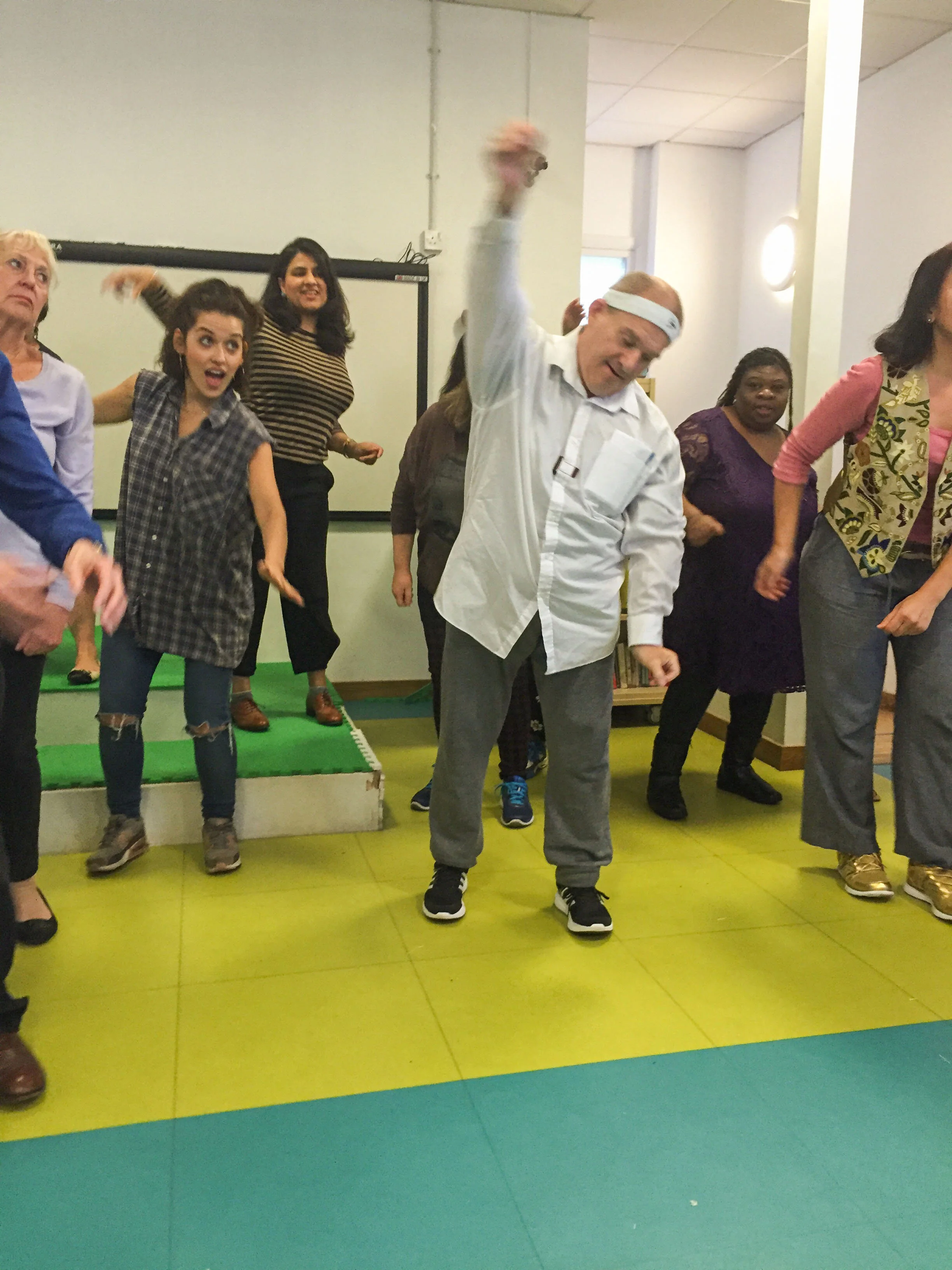 People dancing and having fun together in a room with a green and yellow floor.