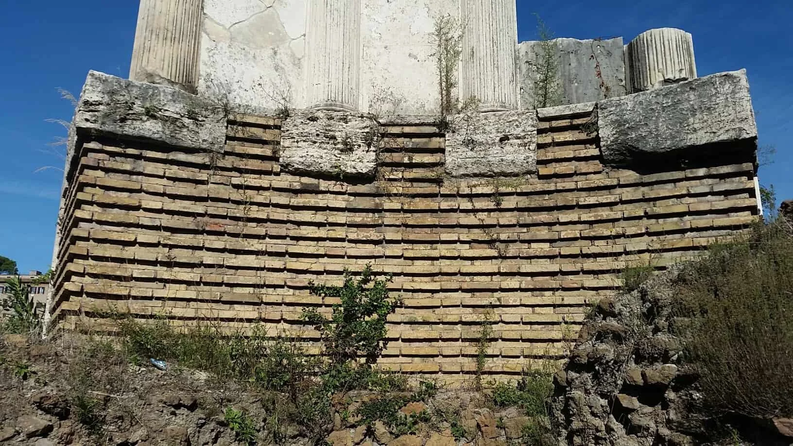 photo depicting brick layers at the base of an ancient temple's ruins, against a blue sky