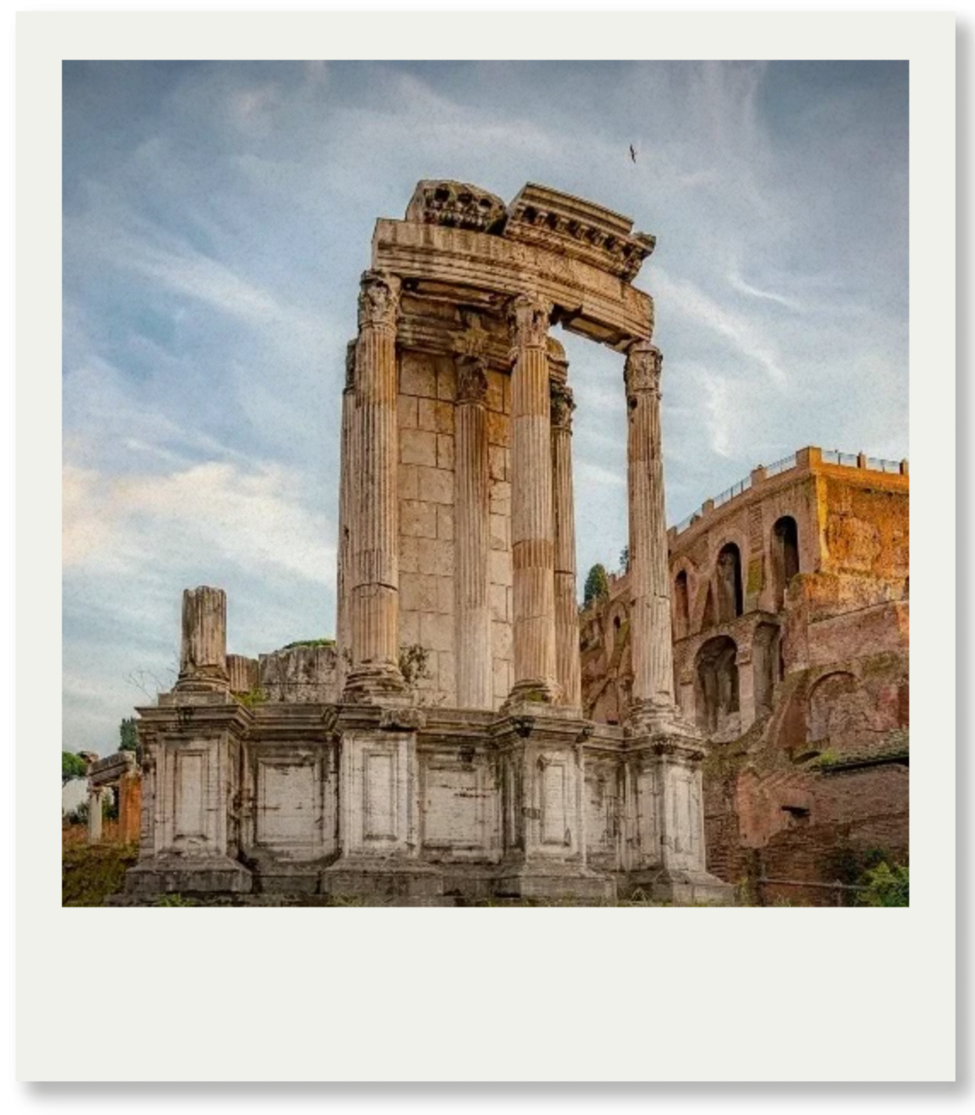 Ancient Roman ruins with tall, weathered columns and partially intact structures against a partly cloudy sky.