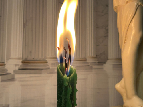 green taper candle burning with large flame