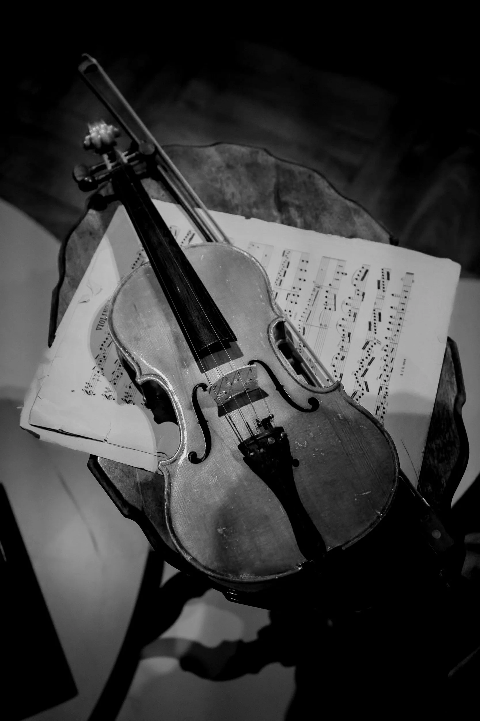 A vintage violin resting on an open sheet music book on a small table, in black and white.