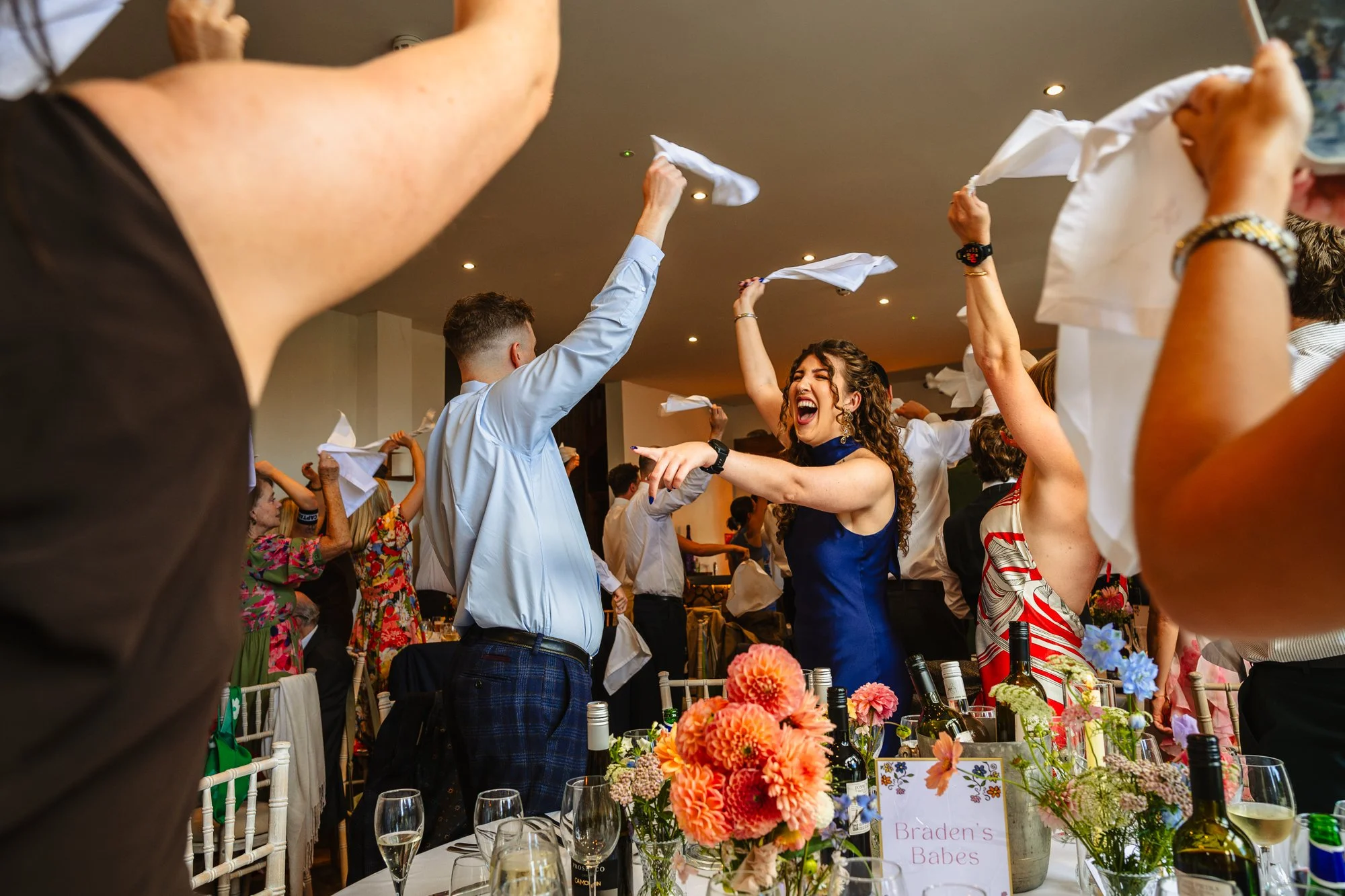 wedding guests wave their napkins in the air in excitement as they wait for the newly married couple to enter the room at Talhenbont Hall