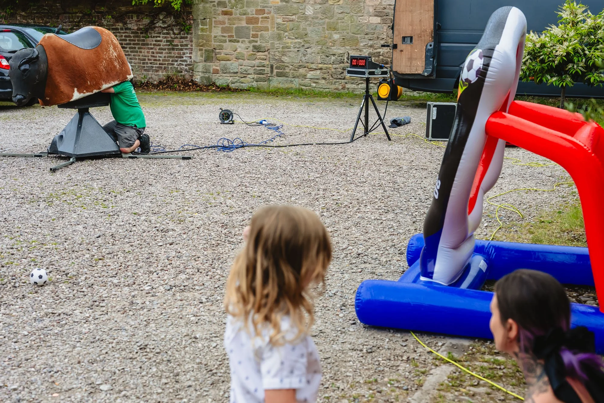 photograph of a young blonde boy and his mother watching a man put a rodeo bull together in a car park by documentary wedding photographer Caroline Goosey