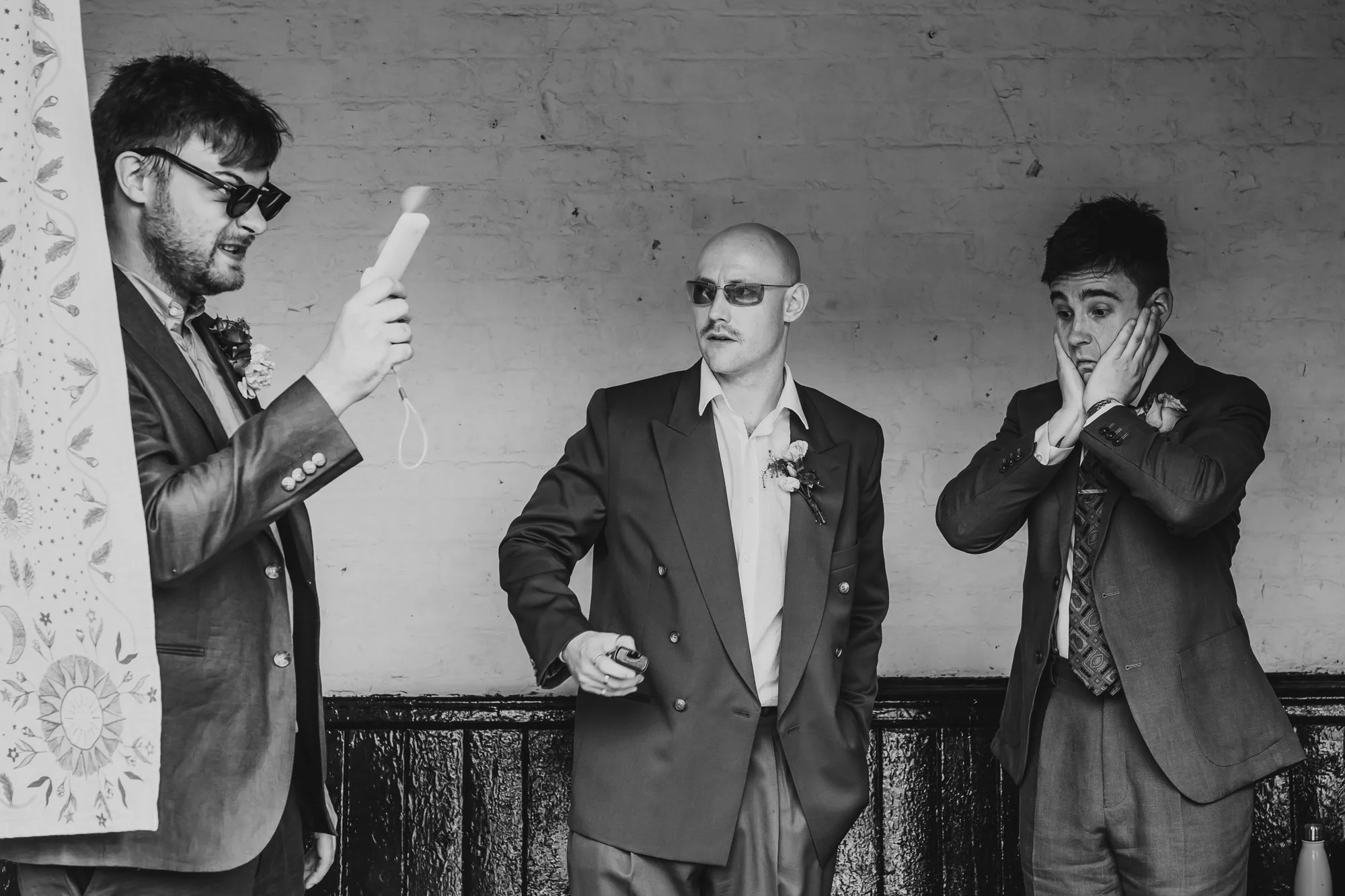  Black and white image of three men with different facial expressions. The man on the right looks extremely nervous. The photo was taken moments before his wedding ceremony was about to begin at the Klondyke in Manchester. 