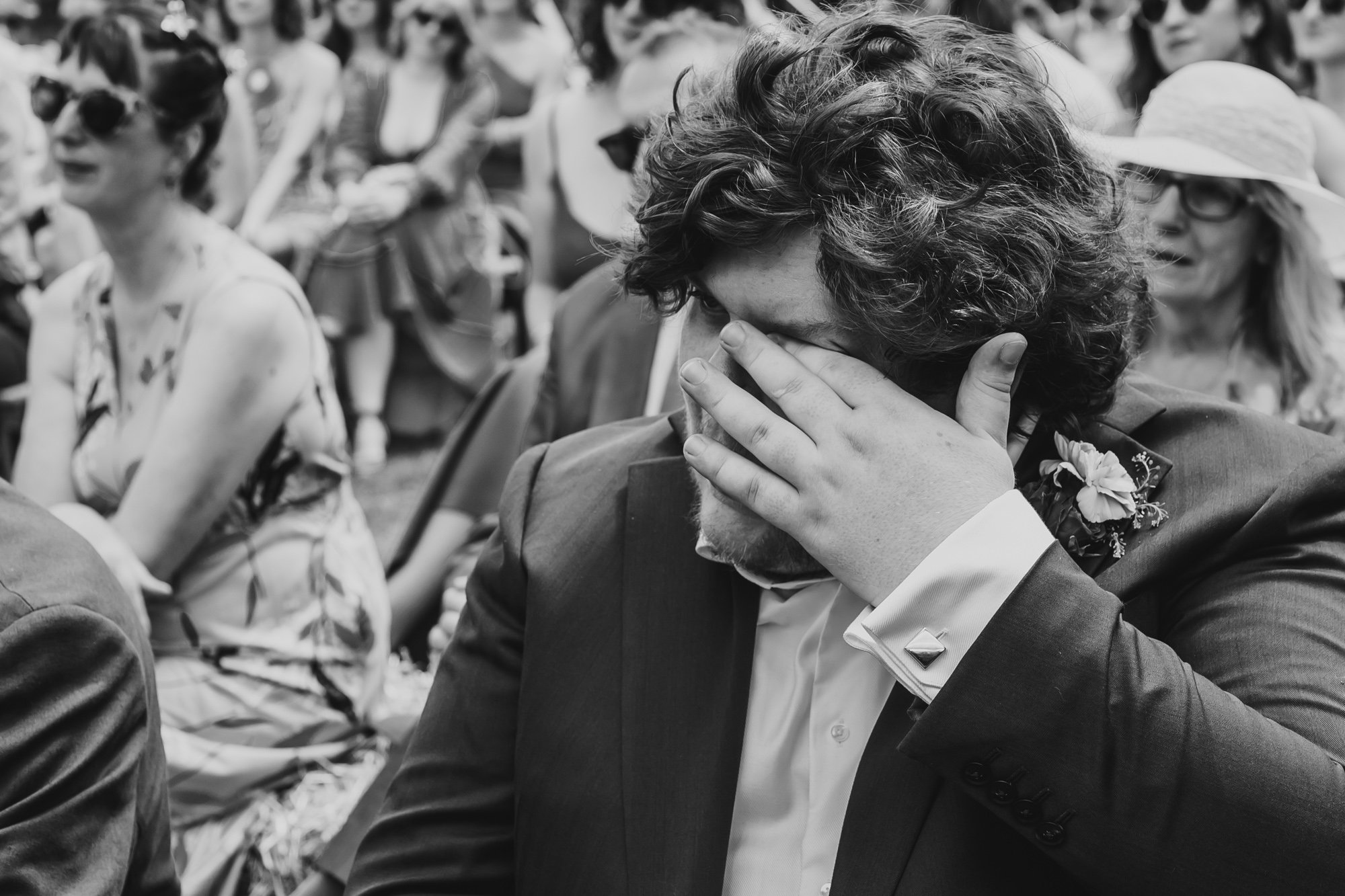  black and white photo of a man wiping tears from his eyes 