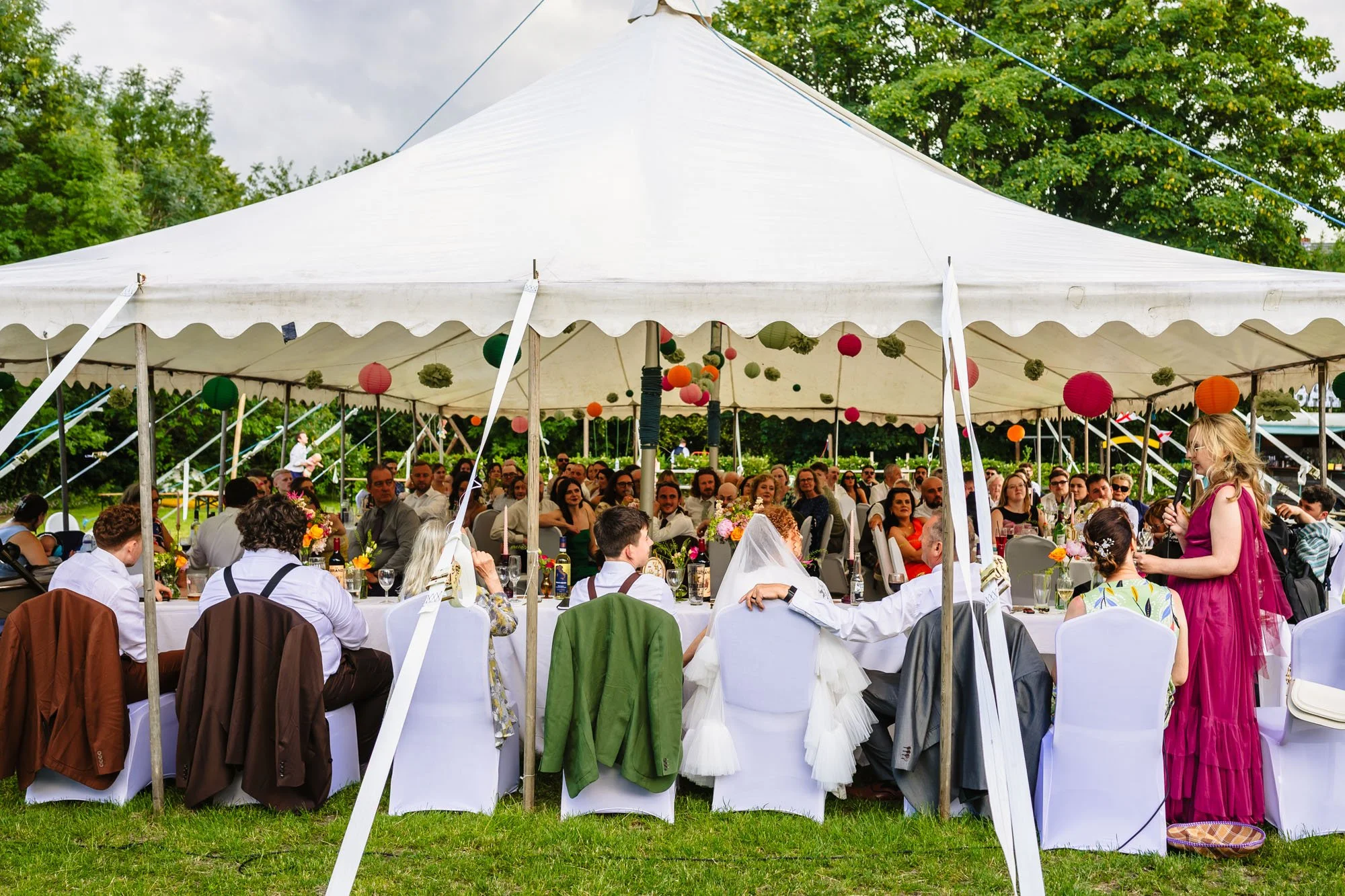  wide photograph of a woman giving a speech in a marquee 