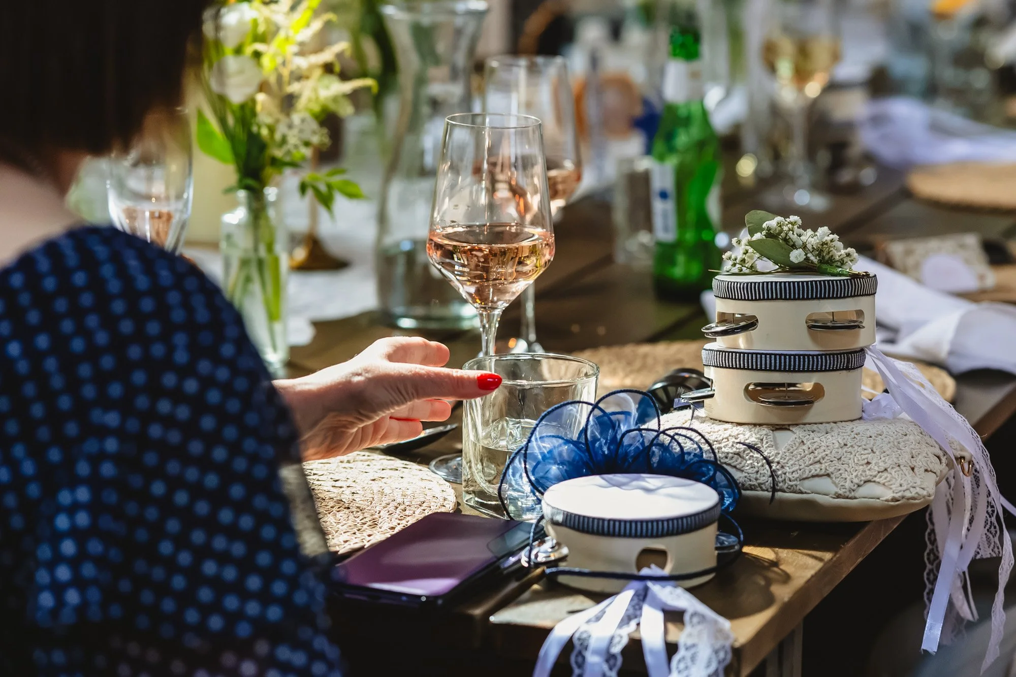 photograph of a woman's hand reaching for a glass of rosé next to small tambourine wedding favours in a blog post about sustainable weddings