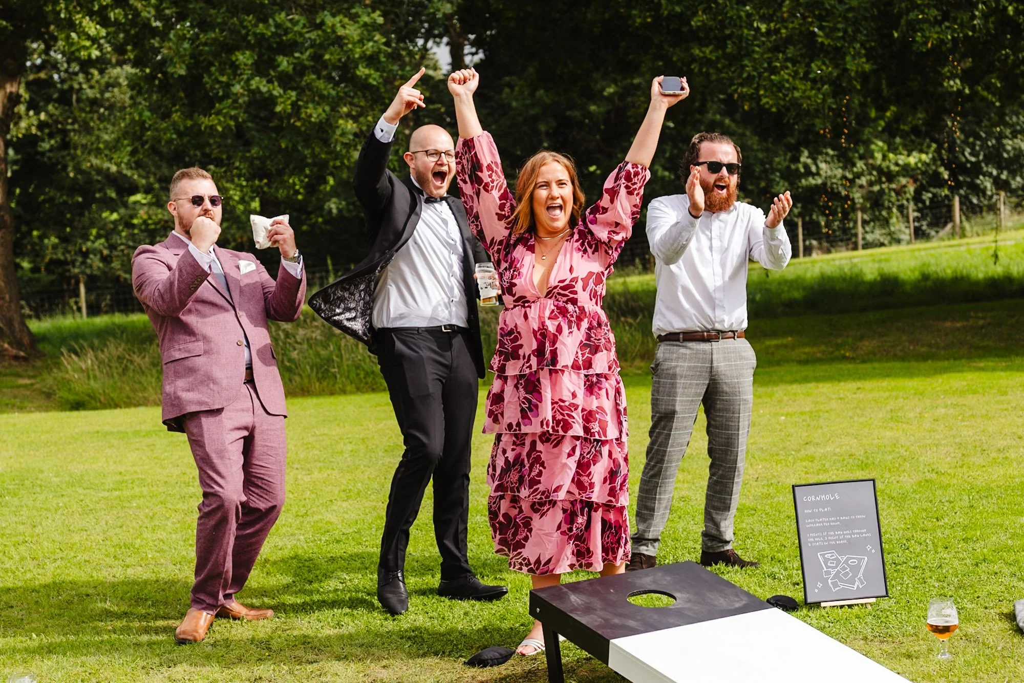 Photograph of 4 wedding guests cheering on a sunny day at Tipis at Riley Green near Preston