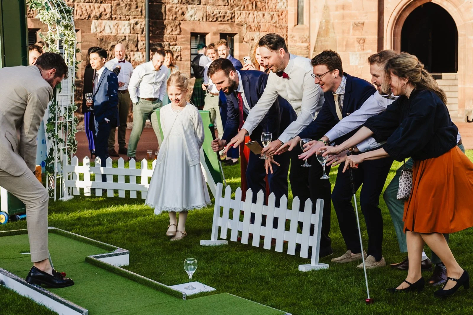 wedding guests play crazy golf during a sunny reception by documentary wedding photographer Caroline Goosey