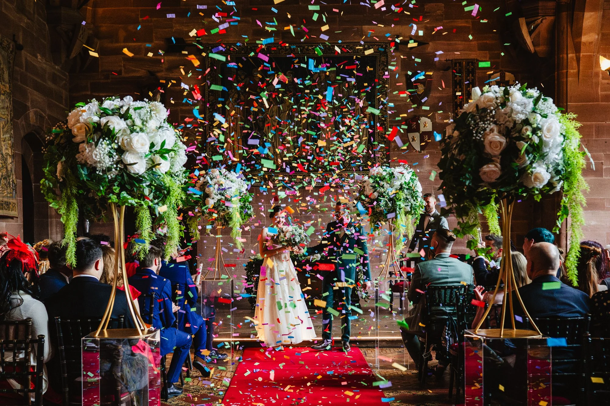 Paper confetti falls through the air at the end of a wedding ceremony at Peckforton Castle in Cheshire