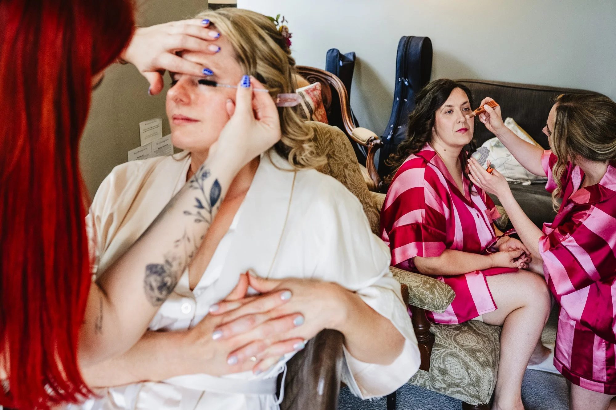 Layered photograph of a bride having her makeup applied while two bridesmaids also do their makeup in the background
