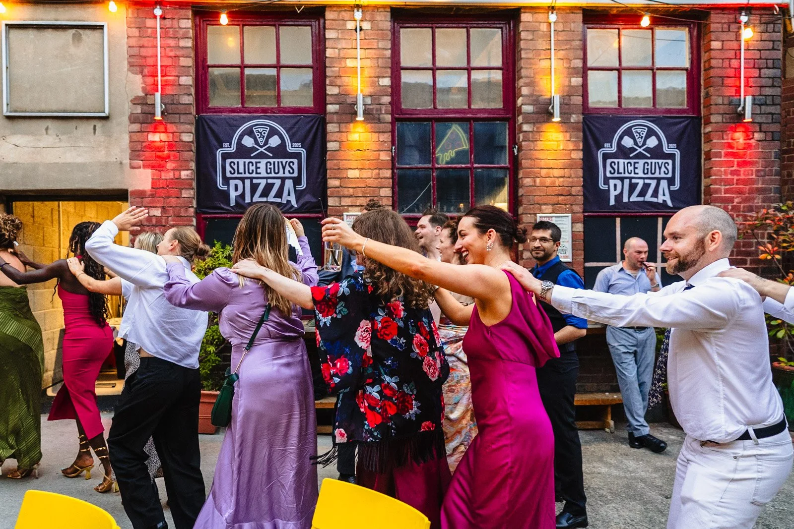 photograph of a group of brightly dressed wedding guests doing a conga line at a wedding at Yellow Arch Studios in Sheffield