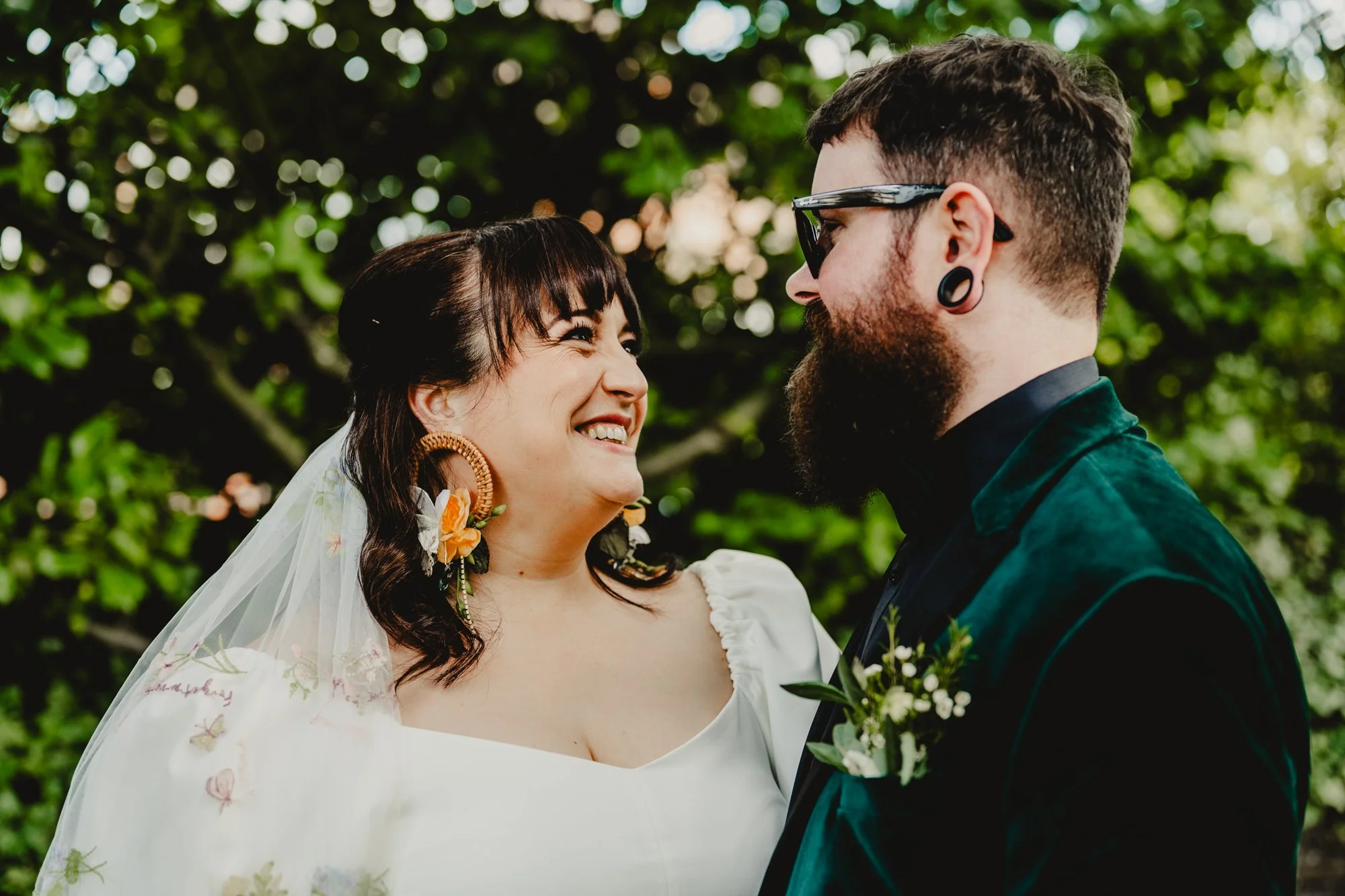 Photograph of a man and woman in the grounds of Didsbury House Hotel. They're an alternative couple - both with extremely impressive earrings. They have just got married and are having portraits taken.