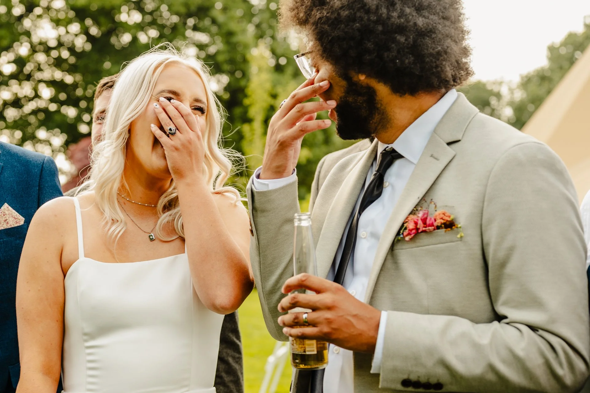 Photograph of a bride and groom laughing together in the afternoon sunshine at their wedding at Tipis at Riley Green