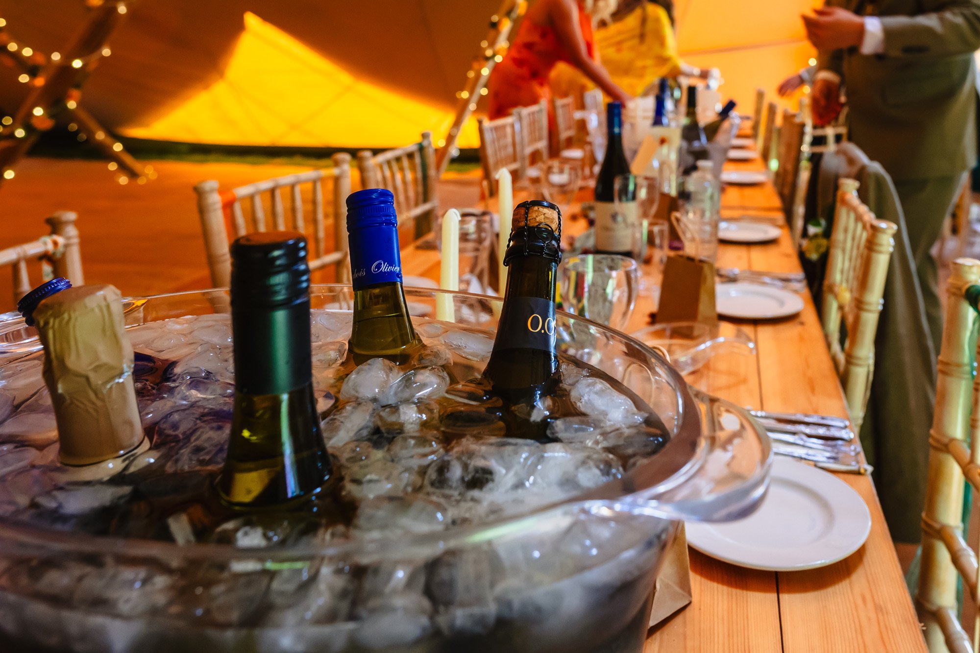photograph of bottles of wine in an ice bucket at a wedding in a tipi - included in a list of sustainable choices at weddings