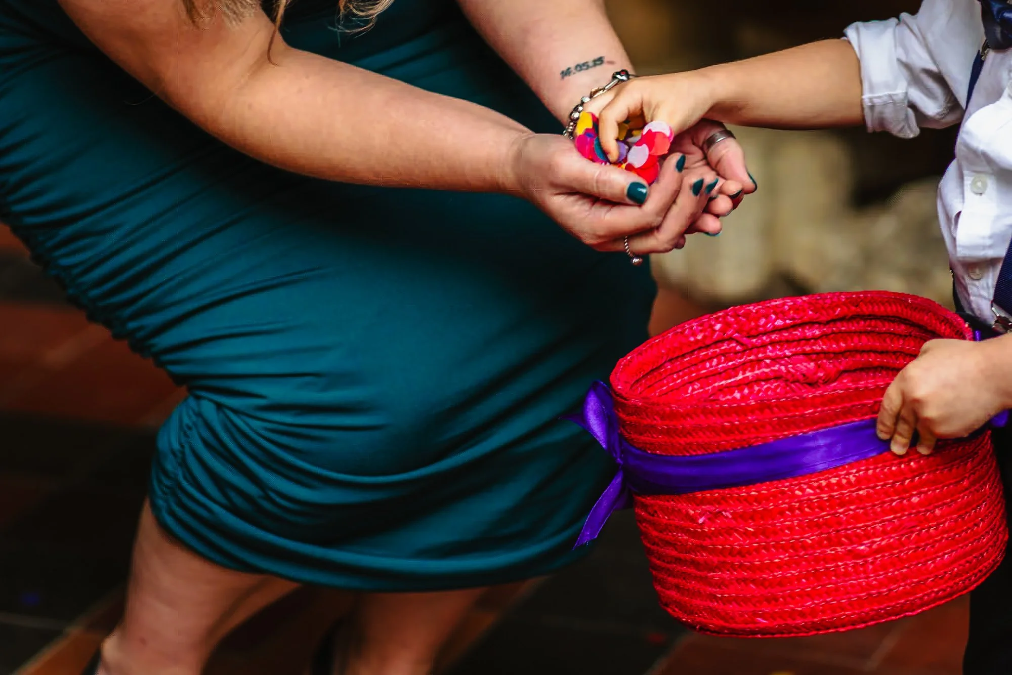 photograph of a small child's hand giving confetti to a woman in a teal dress