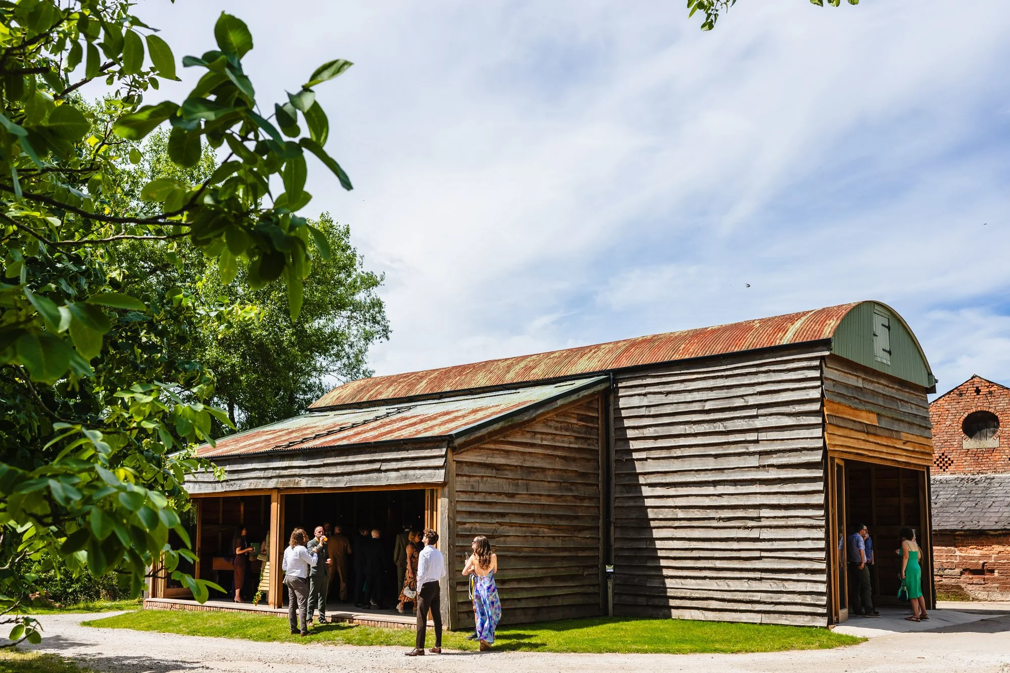 photograph of the barn at Duddon Mill Farm with a few wedding guests milling about.