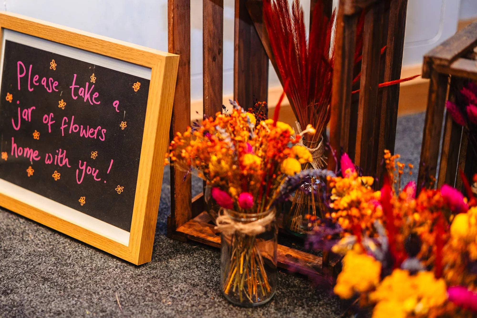 photograph of small vases of dried flowers with a sign telling wedding guests to take some home with them