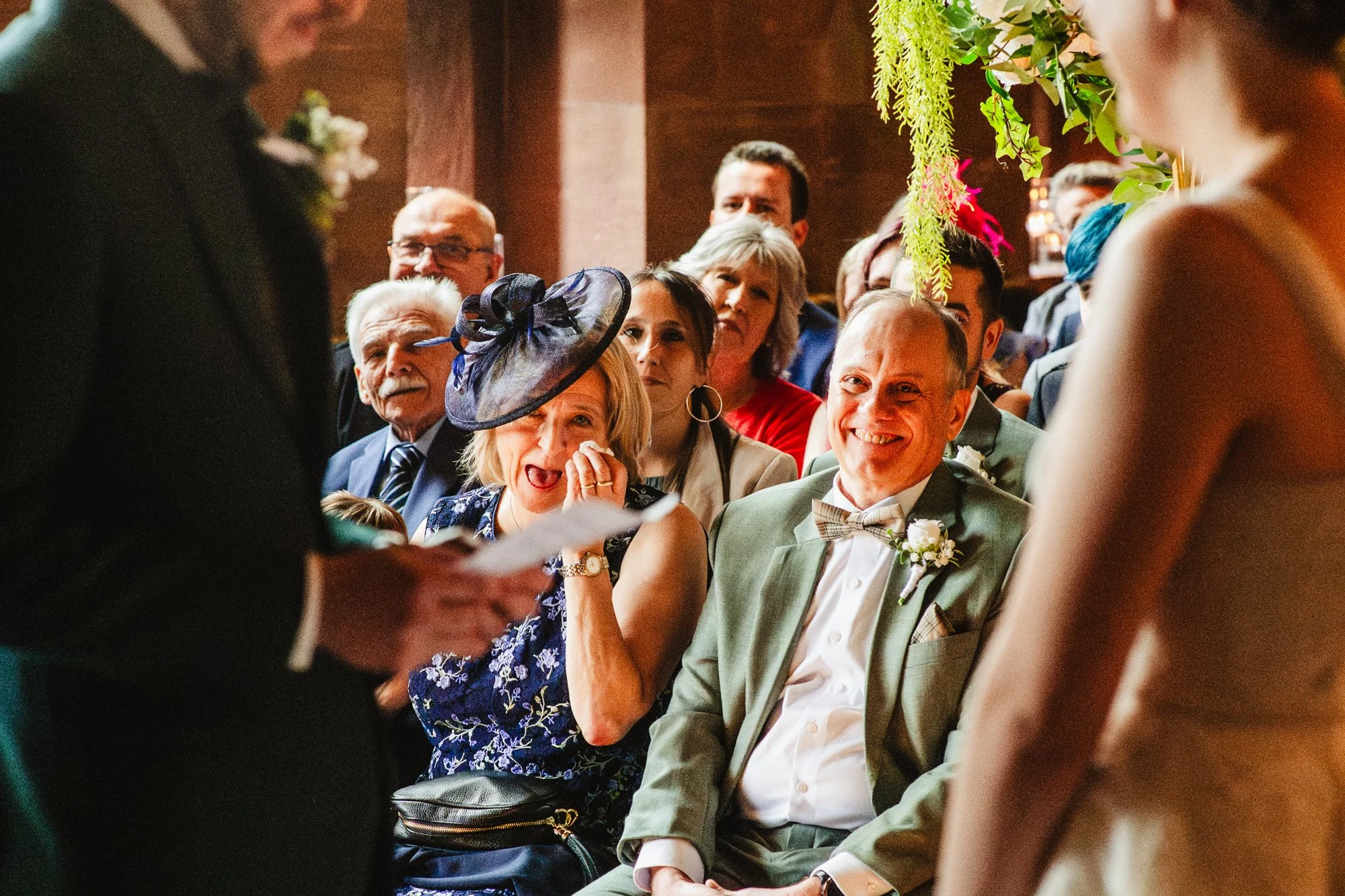 Photograph of a woman dabbing her eyes with a tissue during a wedding ceremony at Peckforton Castle in Cheshire