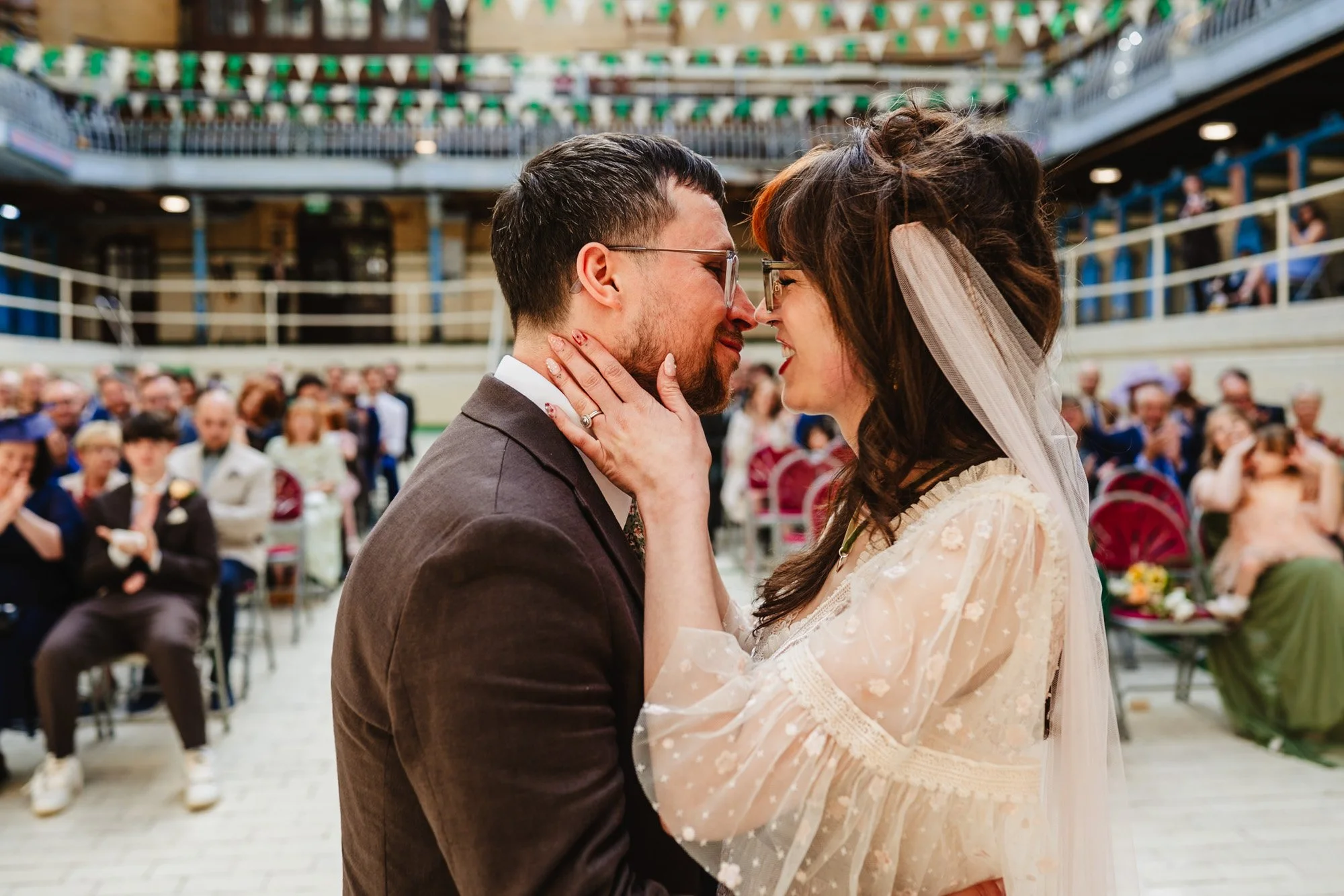 Photograph of a couple having their first kiss during their wedding ceremony at Victoria Baths