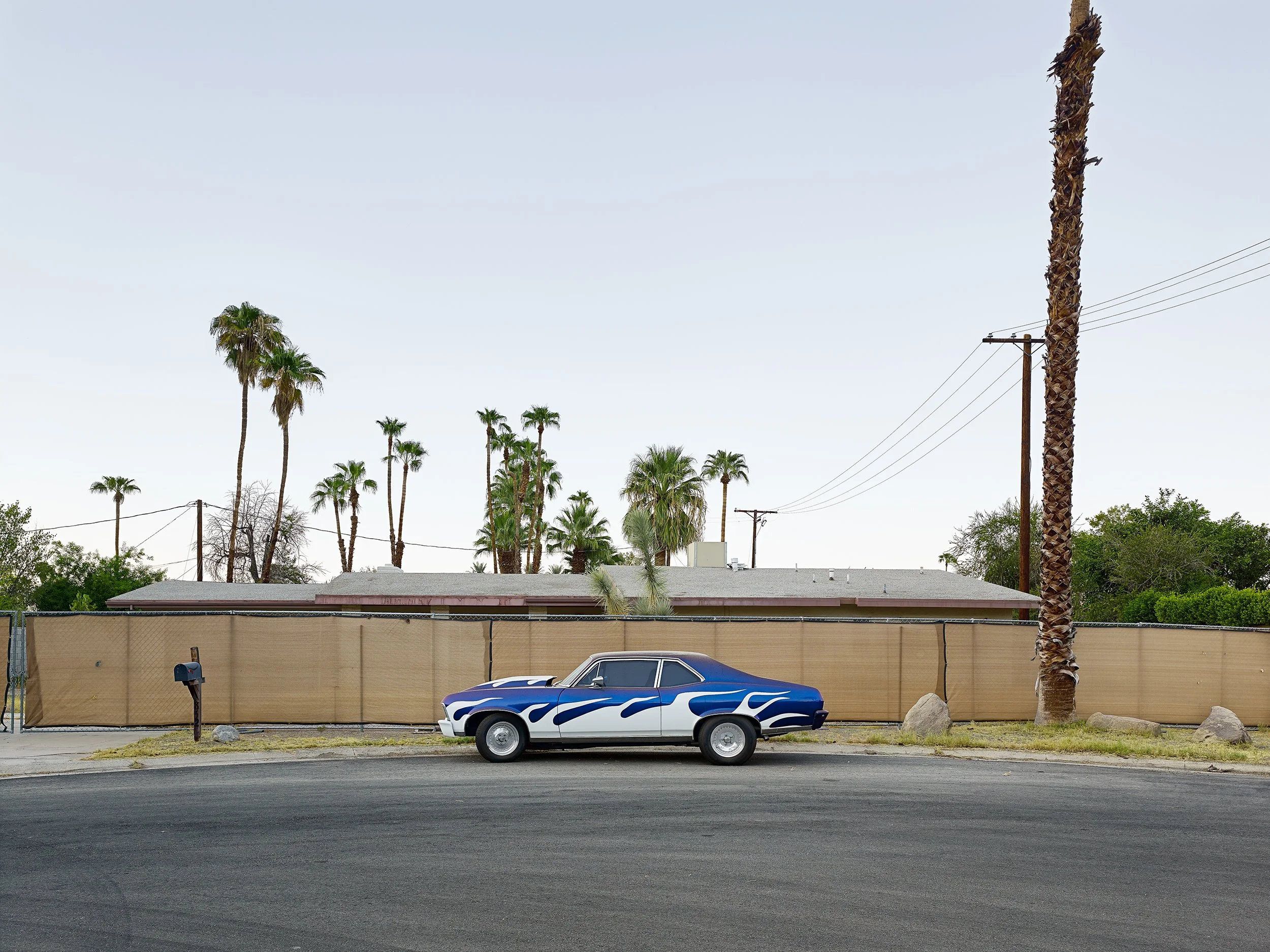 A vintage muscle car, a Chevy painted in blue and white flames, sits in suburbia, California, part of the Lost America series; a multi-award-winning image and honourable mention at the ND Awards.