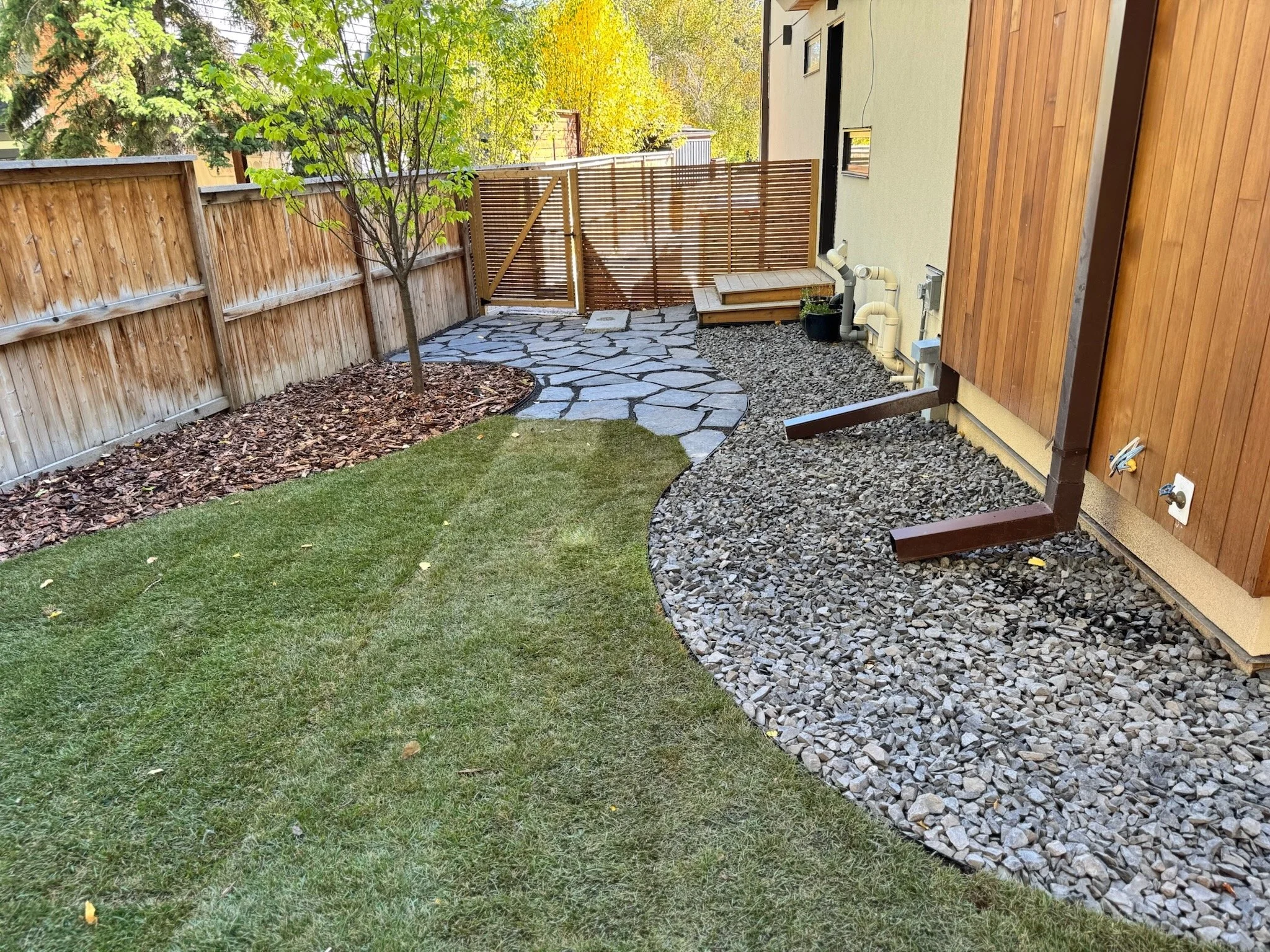 Custom rock and mulch garden bed, sod installation, and natural flagstone path.