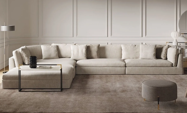 Arnè sectional sofa upholstered in off-white fabric with deep seat cushions, plush throw pillows, and an integrated side terminal bench, set on a plush carpet.