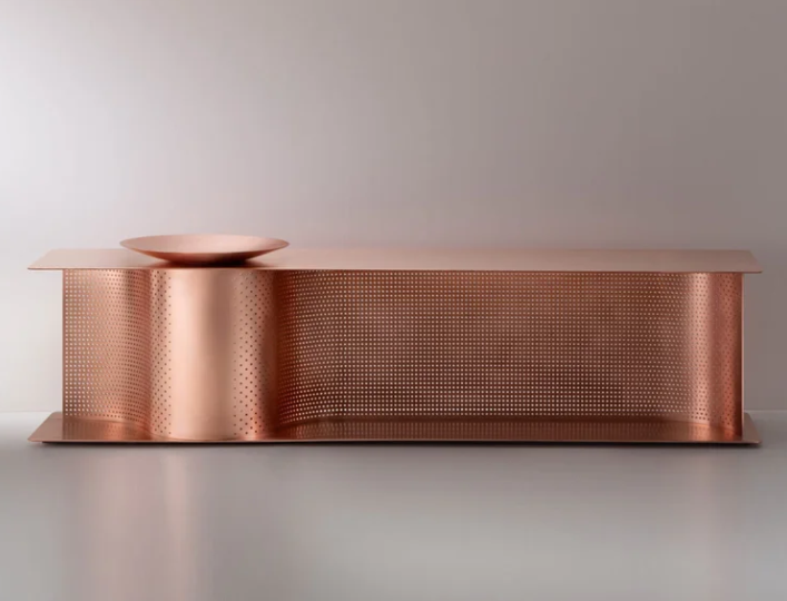 Wave bench featuring a perforated metal base, curved structural support, and an integrated shallow copper bowl on its left surface.