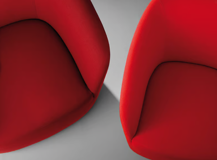 Dep lounge chairs in vibrant red upholstery featuring rounded, sculptural forms with seamless curved backs and seats, photographed from above on a gray surface.
