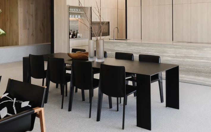 Modern Metallico dining table featuring an ultra-thin black rectangular top and integrated flat side legs, surrounded by matching black dining chairs.