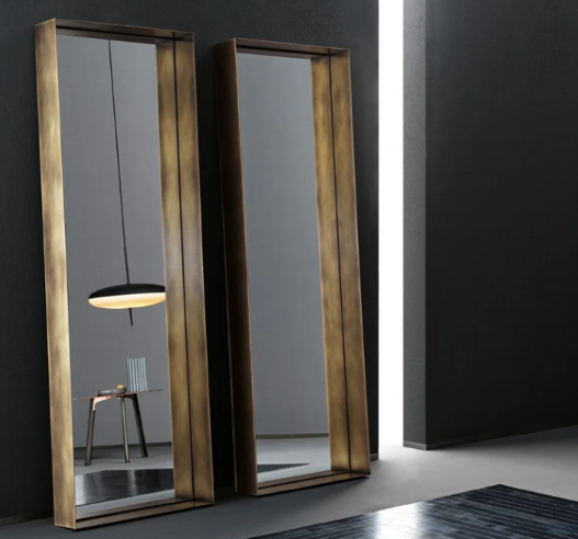 Frame mirrors featuring deep rectangular antique brass frames, leaning side by side against a dark wall in a contemporary interior.