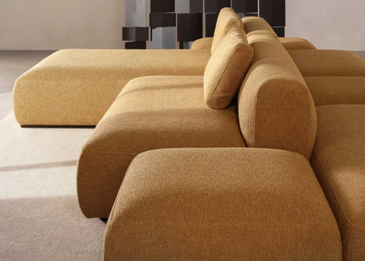 Cosy Island modular sofa upholstered in a warm mustard-yellow textured fabric, featuring low-profile cushioned seats and backrests arranged in a versatile living room setup.