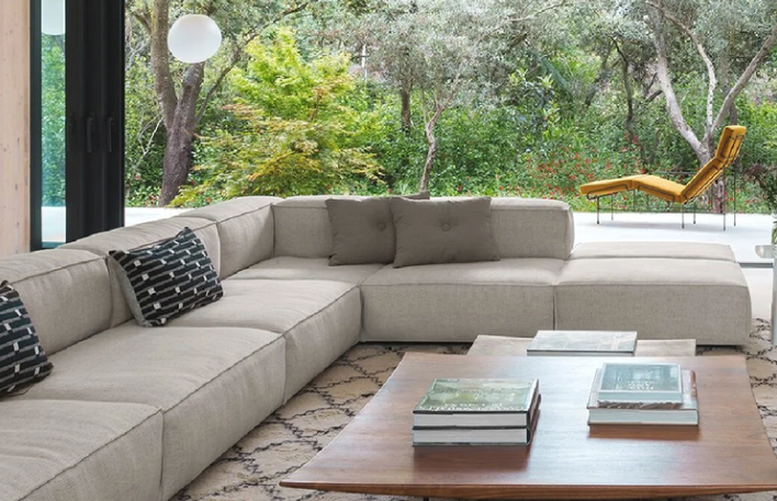 Neowall sectional sofa featuring a low-profile, modular design in light beige fabric, styled with accent pillows and a wooden coffee table in a sunlit room.